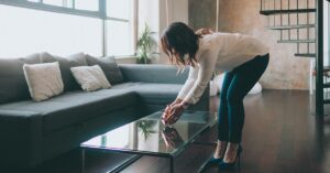 Eine Frau dekoriert das Wohnzimmer eines Hauses mit Home Staging, um die Immobilie auf eine Besichtigung mit Kaufinteressenten vorzubereiten | Home Staging